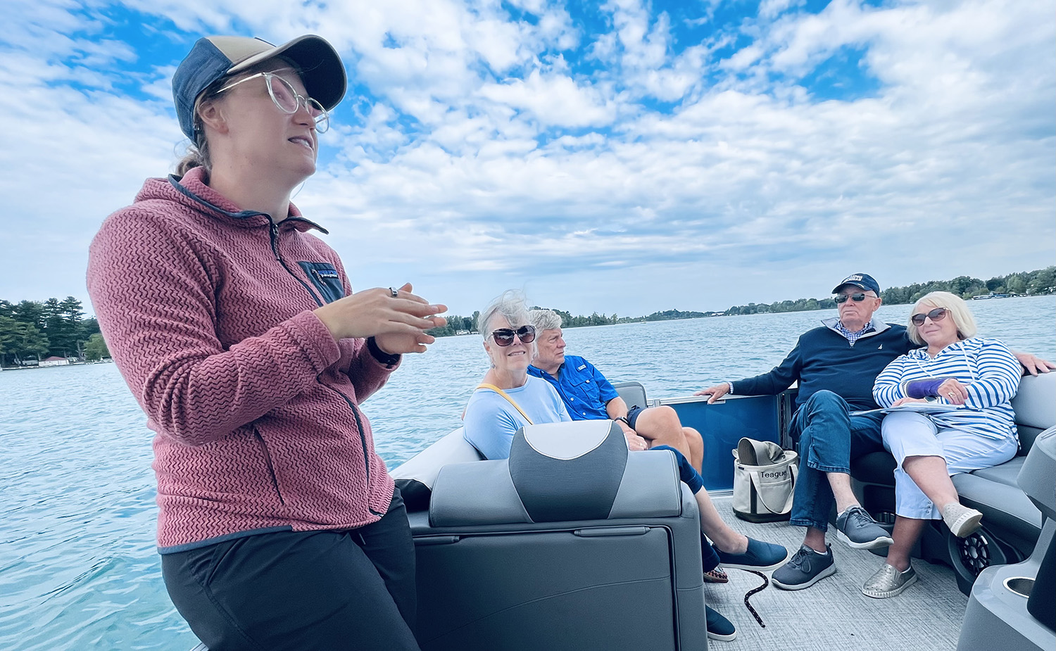 Lake Learning Tours - people on a boat listening to the lake biologist